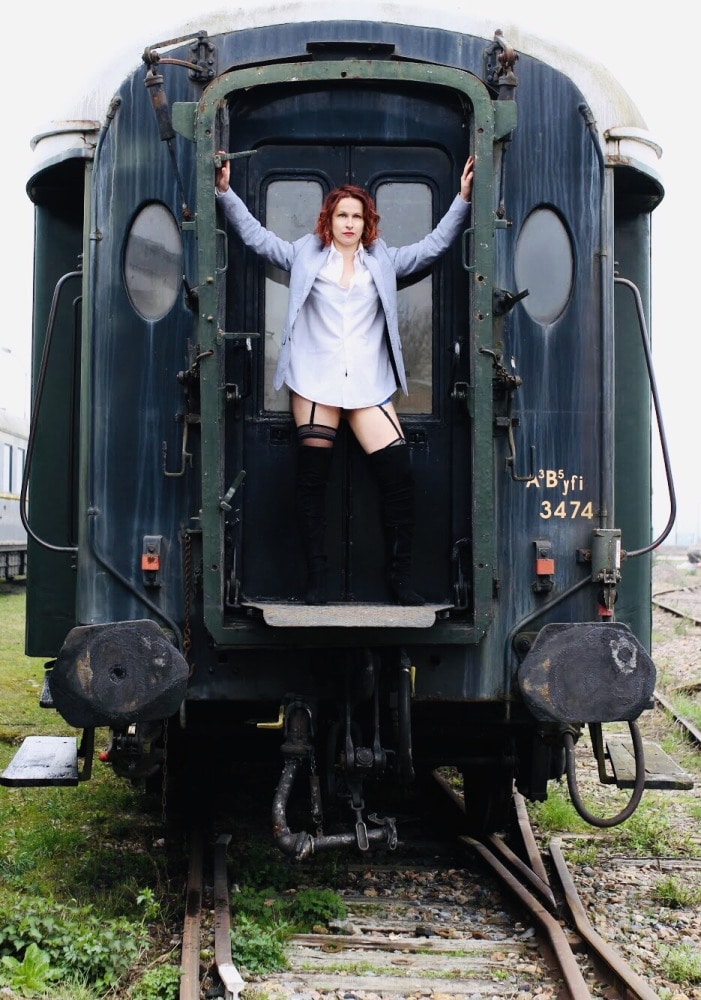 femme en tenue d'homme devant un ancien wagon