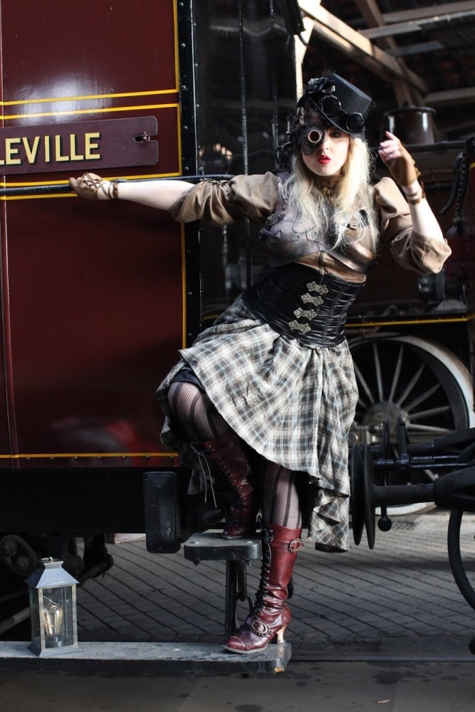femme en costume steampunk devant un ancien wagon