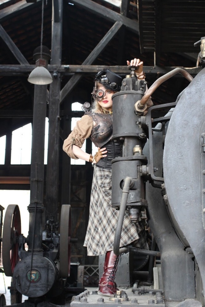 femme en costume steampunk à côté d'une ancienne locomotive 