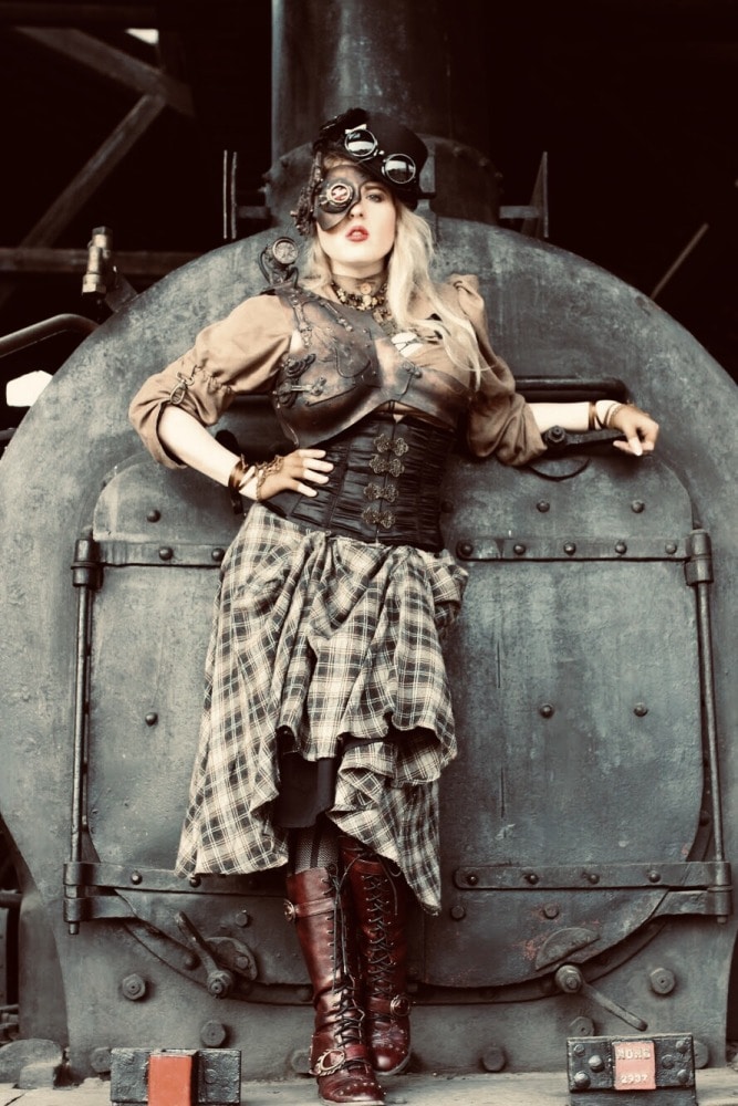 femme en costume steampunk devant une ancienne locomotive