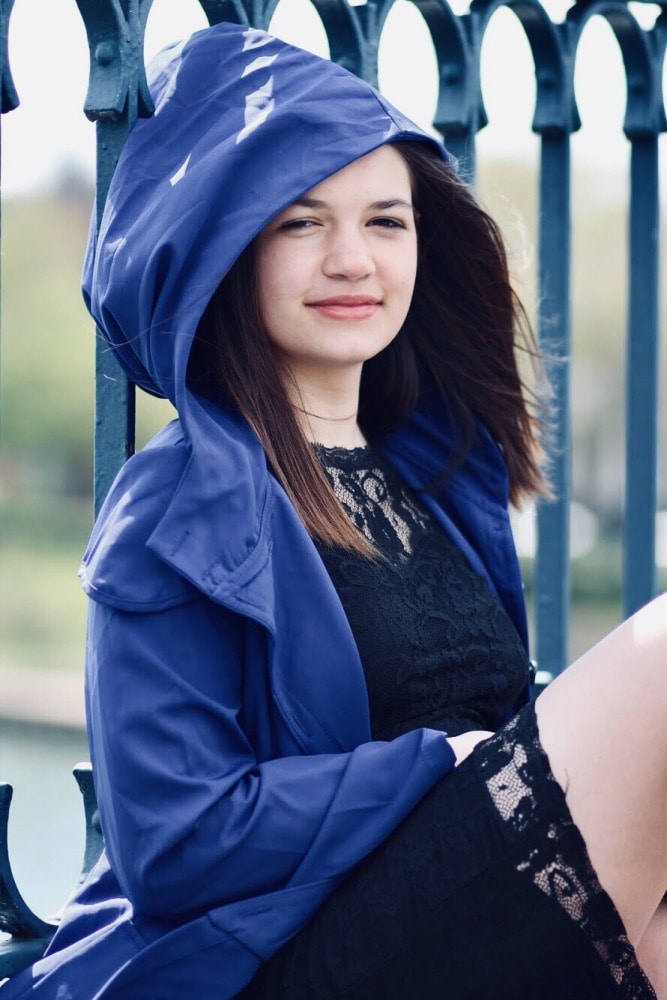 Shooting modele adolescente jeune fille photo-thérapeutique avec Morgane 13 ans en extérieur portant une cape à capuche bleue assise sur un pont robe dentelle noire