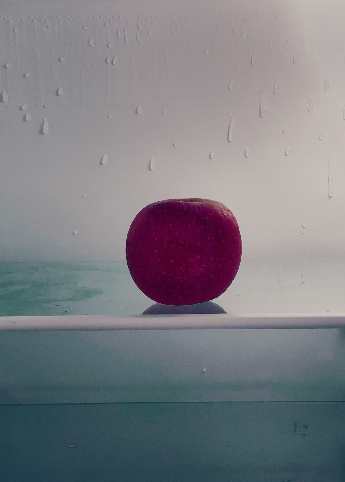 Pomme rouge sur l'étagère d'un frigo dégelé