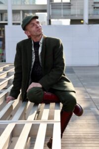 Homme lifestyle en costume vert et casquette assis sur un banc