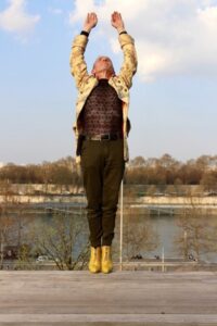 Homme en talons hauts jaunes donnant l'impression de faire un saut en arrière dans un fleuve