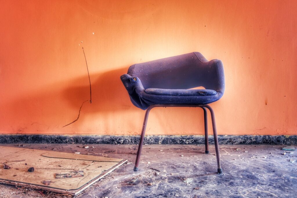 chaise cassée mauve sur un mur orange dans un lieu abandonné