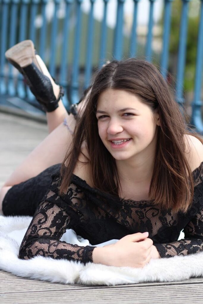Shooting modele adolescente jeune fille photo-thérapeutique avec Morgane 13 ans en extérieur portant une robe dentelle noire allongée sur le sol sur un pont