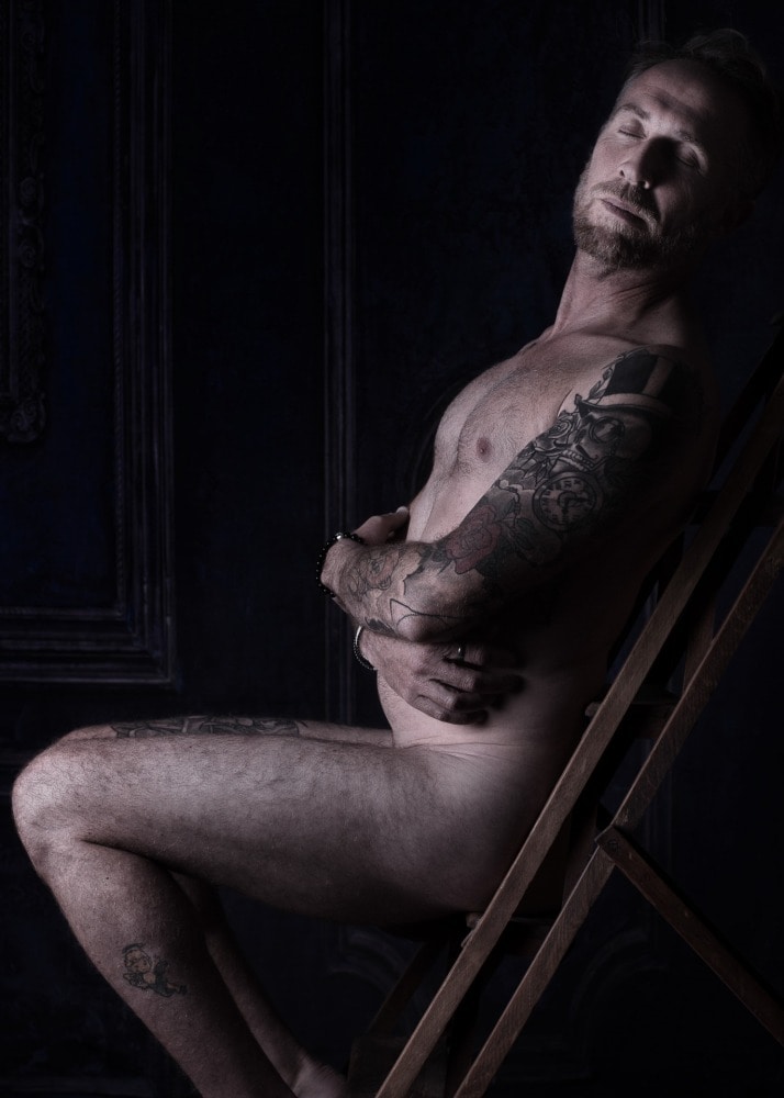 Homme tatoué en nu artistique sur un vieil escabeau