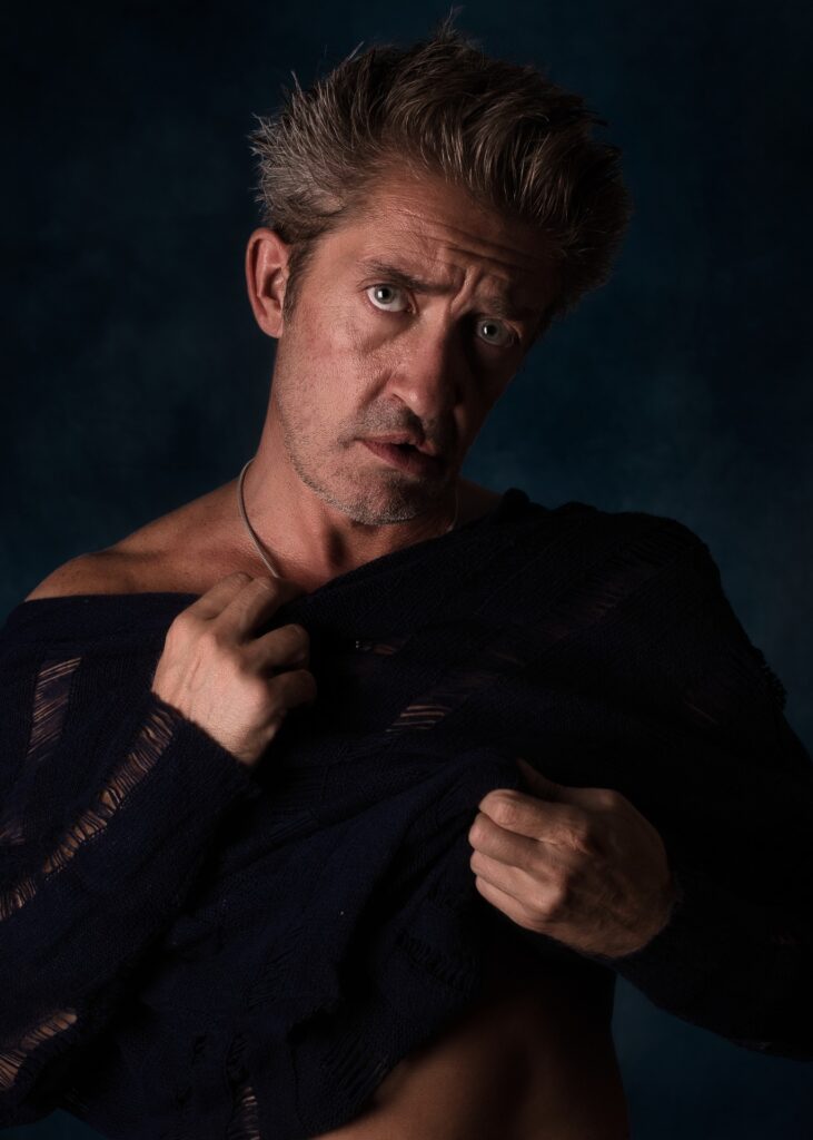 Portrait d'un modèle photo homme avec une gueule en clair obscur en train de se déshabiller