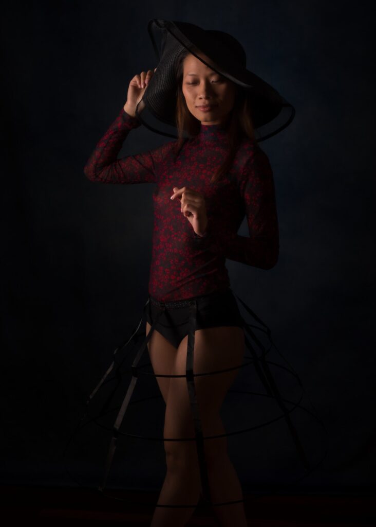 l'estime de soi par la photo boudoir pour femme asiatique en clair obscur portant un chapeau et une crinoline noir