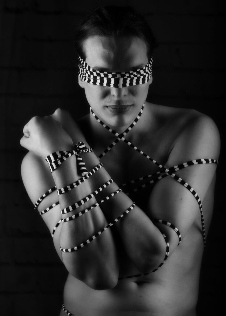 homme en nu artistique noir et blanc et clair obscur attaché par une ficelle en damier