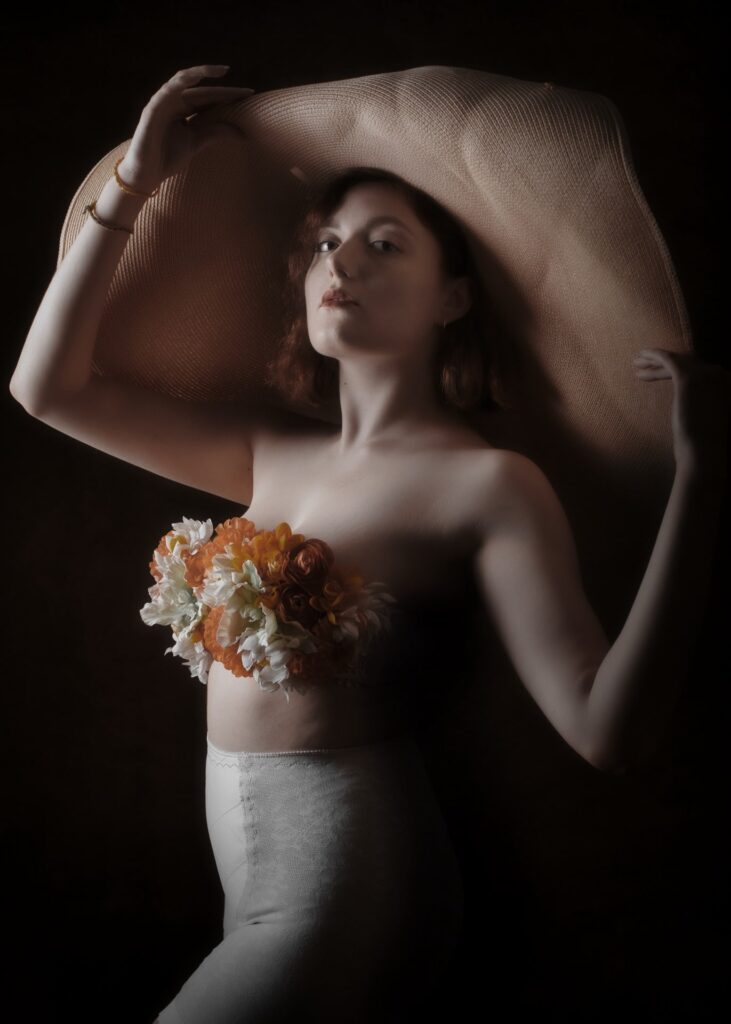 portrait en clair obscur d'une jeune femme modèle portant un grand chapeau et un soutien gorge fleuri culotte gaine ancienne
