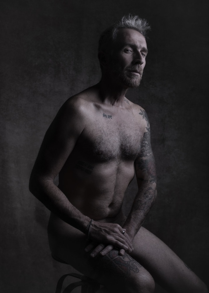 portrait homme barbu et tatoué les cheveux blancs assis sur un tabouret de bar