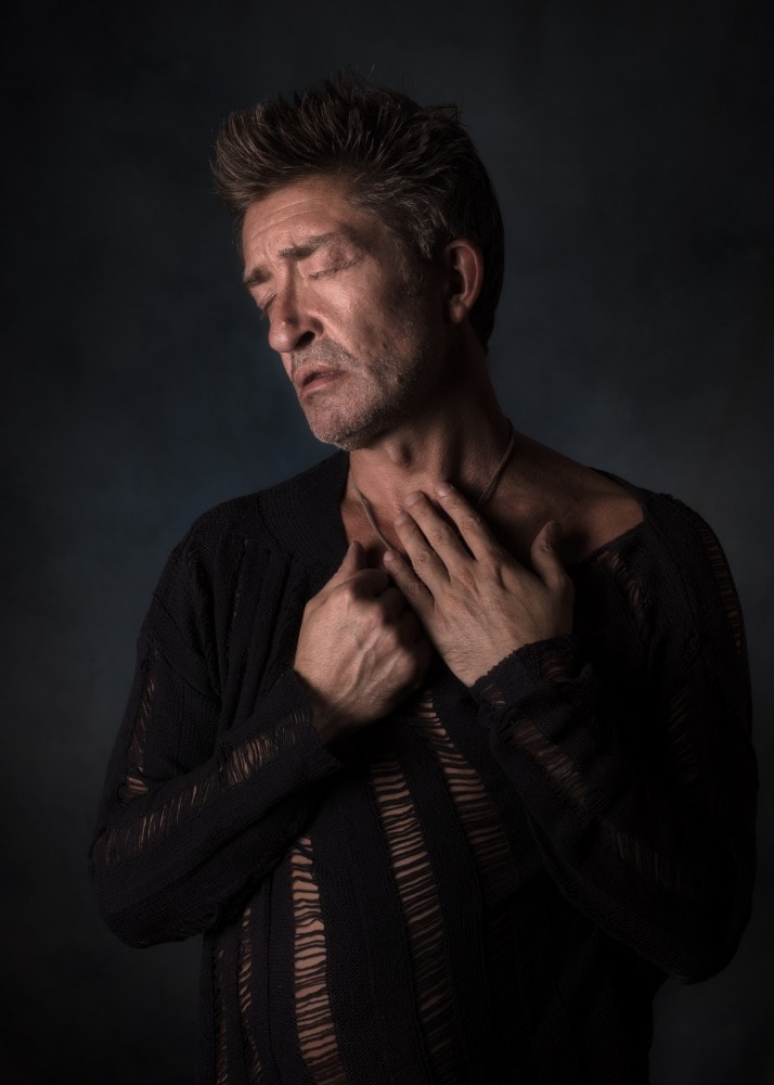 modèle photo homme mature avec cicatrice les yeux fermés et les mains dans son cou le visage de profil