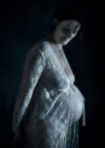 femme enceinte de profil dans un peignoir en dentelle blanche