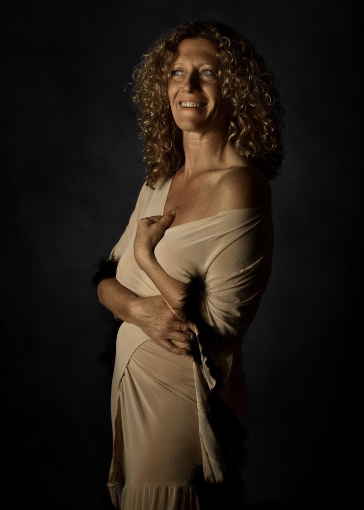 femme aux cheveux dorés bouclés dans un peignoir beige sourire