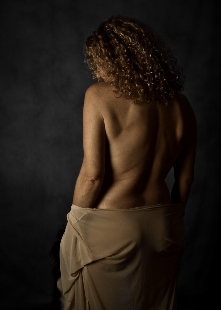 femme aux cheveux dorés bouclés de dos dans un peignoir tombant