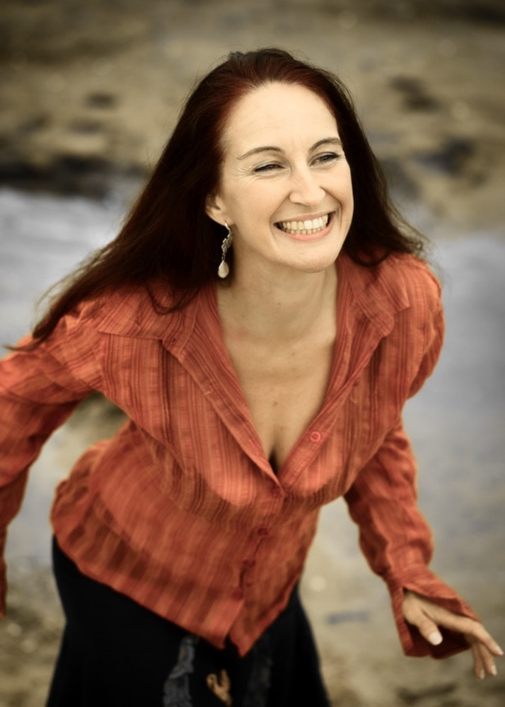 portrait d'une femme aux cheveux longs souriant dans la nature chemisier orange