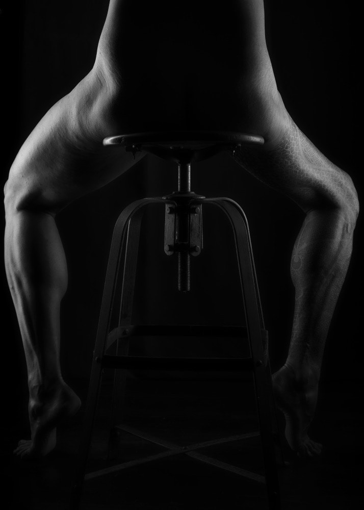 jambes d'homme en clair obscur sur un tabouret ancien une jambe tatouée atrophiée