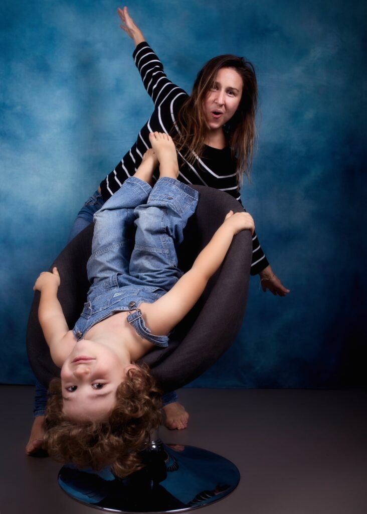 enfant petit garçon moins de 5 ans posant avec sa maman sur un fauteuil la tête à l'envers