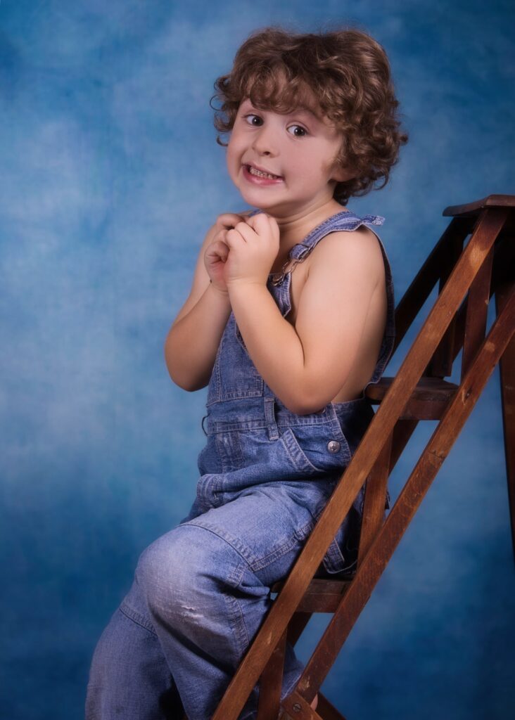 enfant petit garçon moins de 5 ans portrait posant les mains jointes sur un escabeau