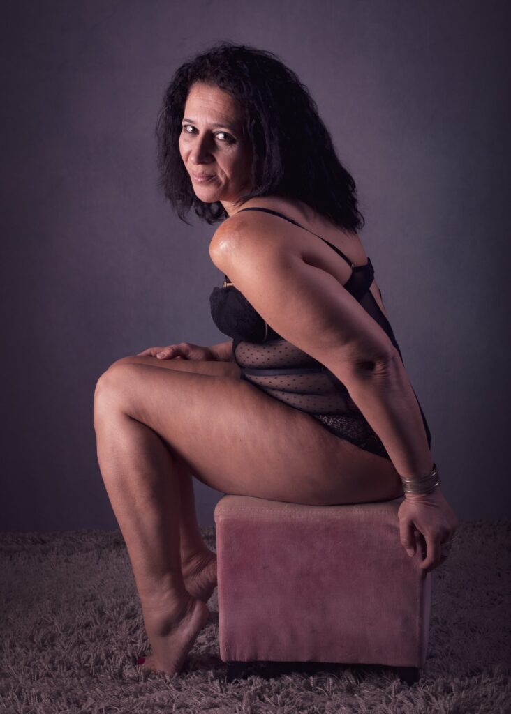 séance photo thérapeutique estime de soi pour femme mature par céline pivoine eyes femme photographe près de Paris sur un cube rose en lingerie dentelle noire peau brûlée