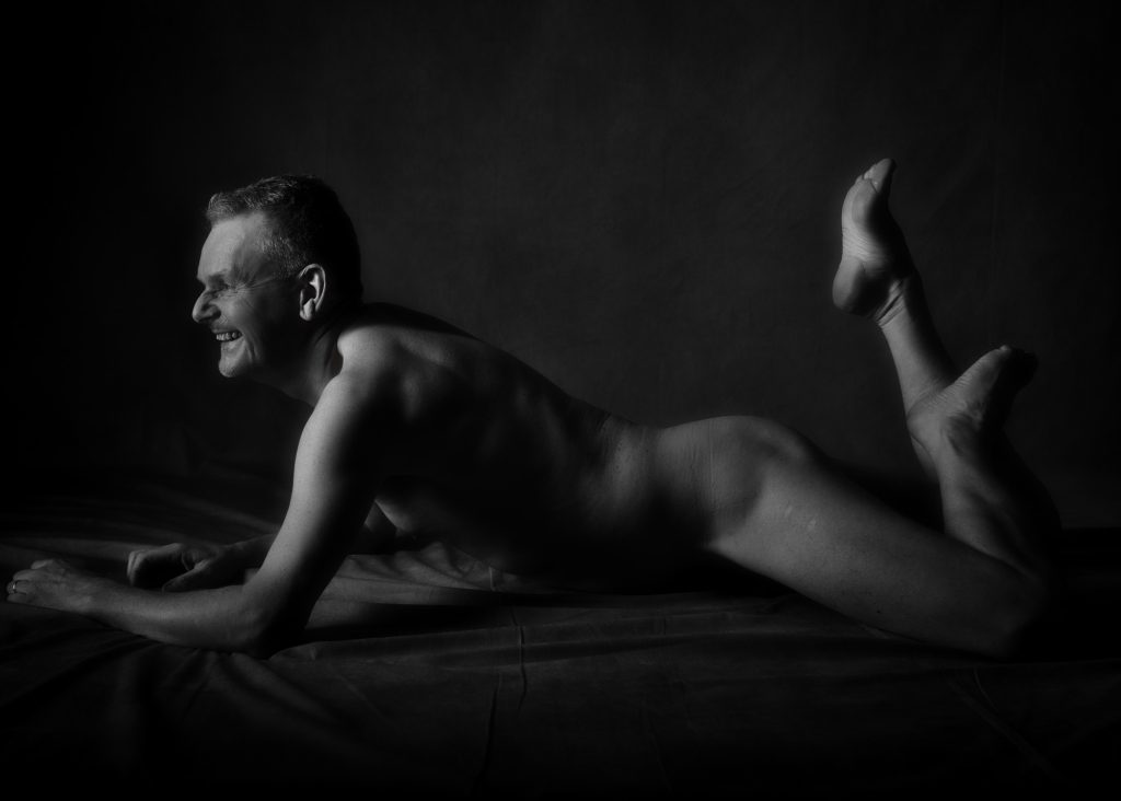 Séance photo estime de soi nu artistique pour homme mature sénior silver sourire et clair obscur sur le sol au studio photo de Céline Pivoine Eyes à Montreuil près de Rosny sous bois