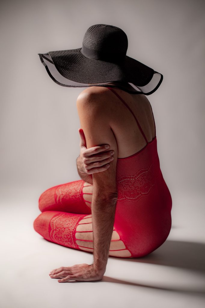 séance boudoir pour homme au féminin travestis combinaison rouge jarretelles et chapeau par femme photographe Céline Pivoine Eyes au studio photo location à Montreuil près de Nogent sur Marne