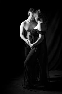 Séance grossesse pour couple photographe famille enceinte avec Sarah et Benoît en robe noire longue debout par céline pivoine eyes femme photographe au studio photo location à Montreuil 93 en Ile de France