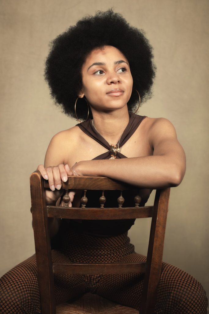Séance book polas mannequin pour agence avec Séréna estime de soi métisse cheveux afro par femme photographe Celine Pivoine eyes au studio photo location à Montreuil 93 près de Paris tenue marron et chaise ancienne portrait