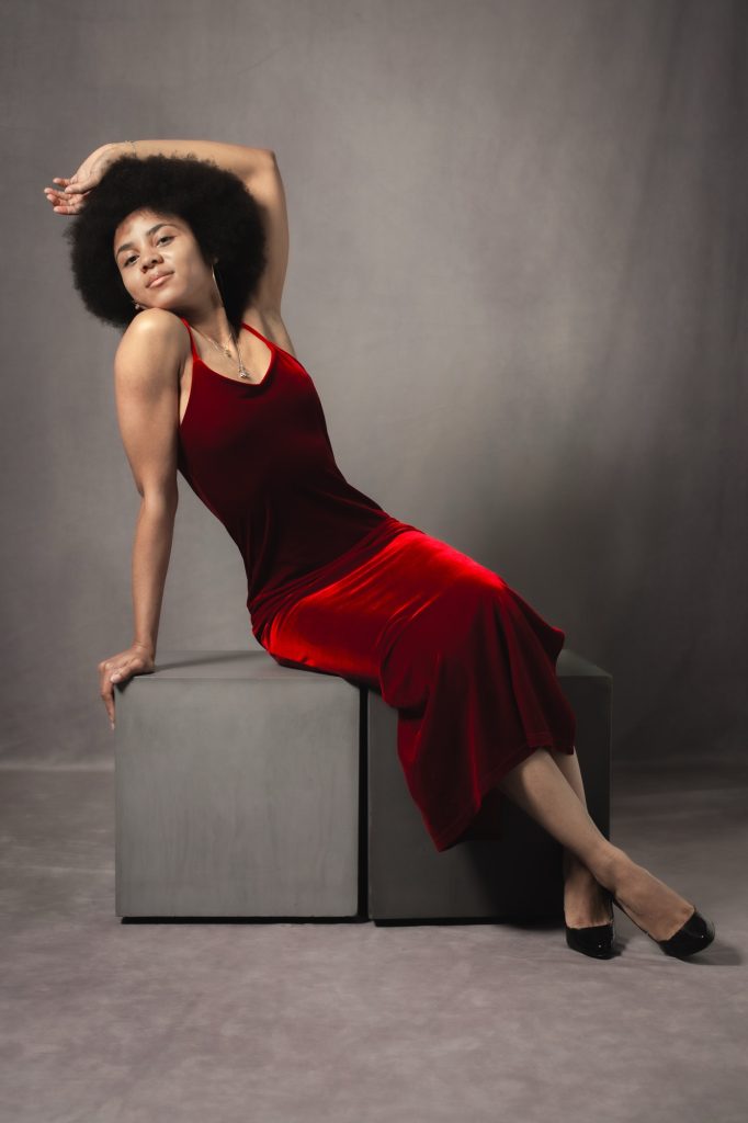 Séance book polas mannequin pour agence avec Séréna estime de soi métisse cheveux afro par femme photographe Celine Pivoine eyes au studio photo location à Montreuil 93 près de Noisy le sec assise cube robe rouge velours talon