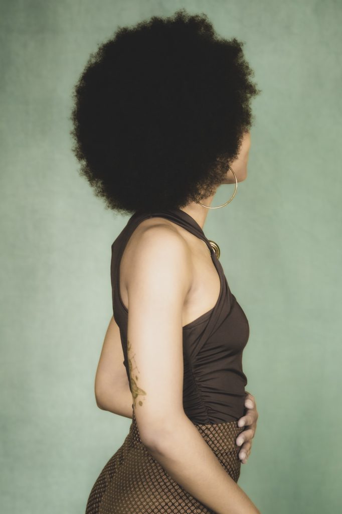 Séance book polas mannequin pour agence avec Séréna estime de soi métisse cheveux afro par femme photographe Celine Pivoine eyes au studio photo location à Montreuil 93 près de Nogent sur Marne de dos débardeur marron debout