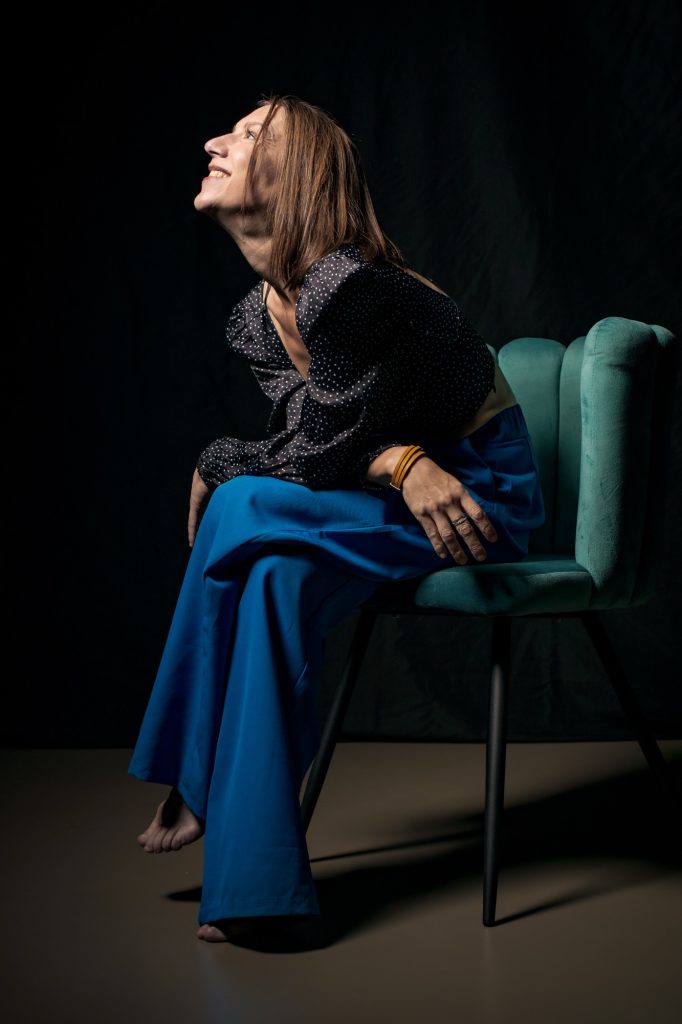 Séance photo shooting estime de soi confiance pour femme TCA trouble du comportement alimentaire anorexique maigre avec Céline 39 ans par Céline Pivoine Eyes femme photographe au studio photo location à Montreuil 93 près de Noisy le sec sourire sur un fauteuil vert pantalon bleu