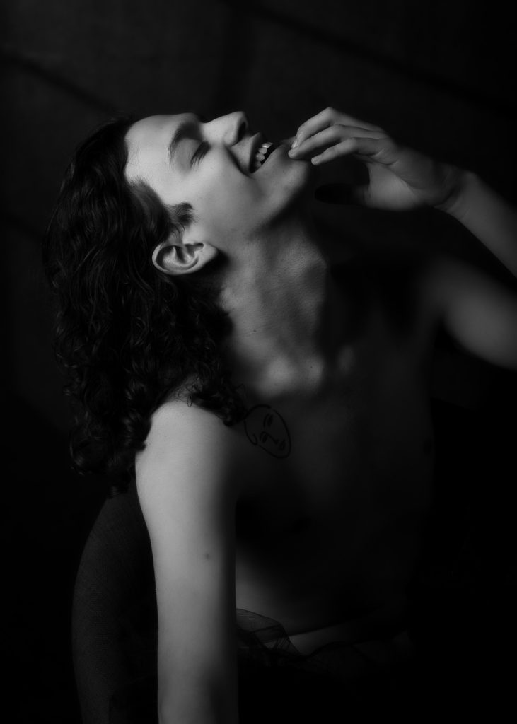 séance photographe queer lgbtqia+ androgyne série les féminins avec Thom homme modèle débutant par céline pivoine eyes femme photographe au studio photo location à Montreuil 93 près de Vincennes portrait noir et blanc mains cheveux bouclés profil sourire