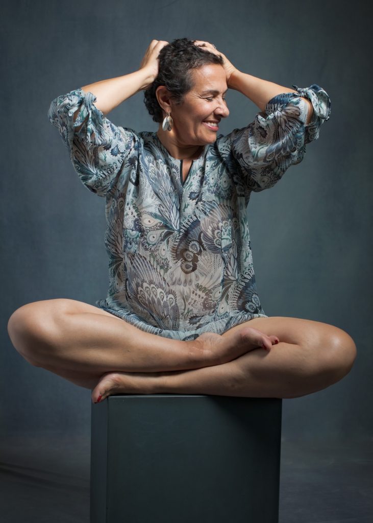 séance photo résilience cancer maladie estime de soi pour femme sénior mature sexagénaire avec Myriam par Céline pivoine eyes femme photographe au studio photo location à Montreuil 93 près de Fontenay sous bois assise sur cube chemise bleue sourire