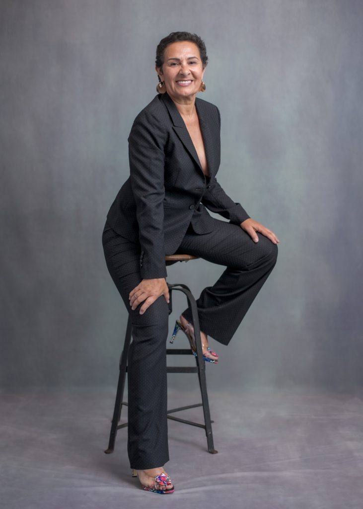 séance photo résilience cancer maladie estime de soi pour femme sénior mature sexagénaire avec Myriam par Céline pivoine eyes femme photographe au studio photo location à Montreuil 93 près de Vincennes sourire en costume pantalon noire sur tabouret