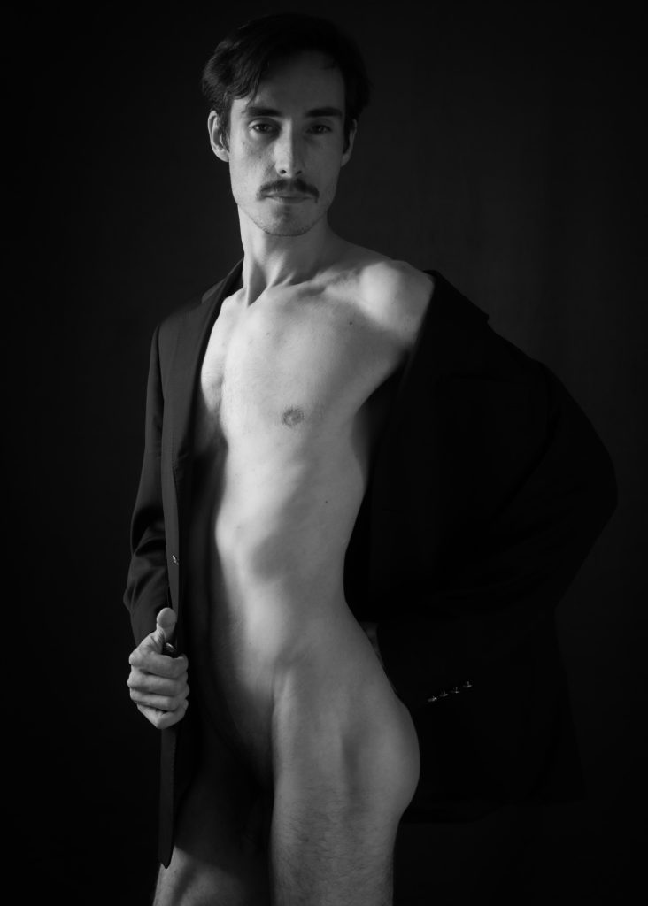 séance photo shooting pour modèle homme mince musclé lgbtqia avec Christophe Gallo acteur par femme photographe céline pivoine eyes au studio photo location à Montreuil près de Paris nu artistique noir et blanc dans veste noire debout moustache