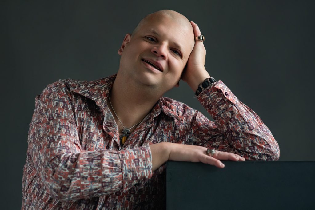 Séance photo professionnelle pour artiste chanteur non voyant pochette de disque album cd musique Franck Pruvost sourire portrait posé sur un cube chemise