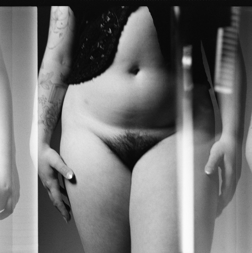 Séance confiance en soi boudoir artistique pour jeune femme pulpeuse ronde argentique pantalon six TL noir et blanc grain debout pubis poils ventre frontal