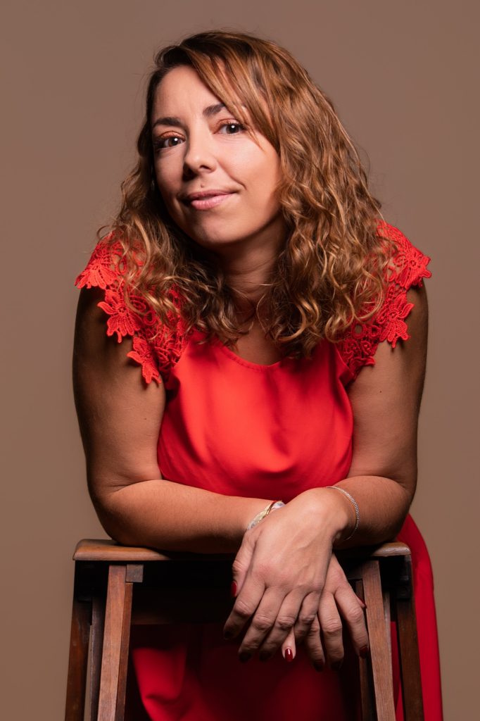 Séance portrait estime de soi avec Vanessa cheveux bouclés en robe corail saumon accoudée sur un escabeau