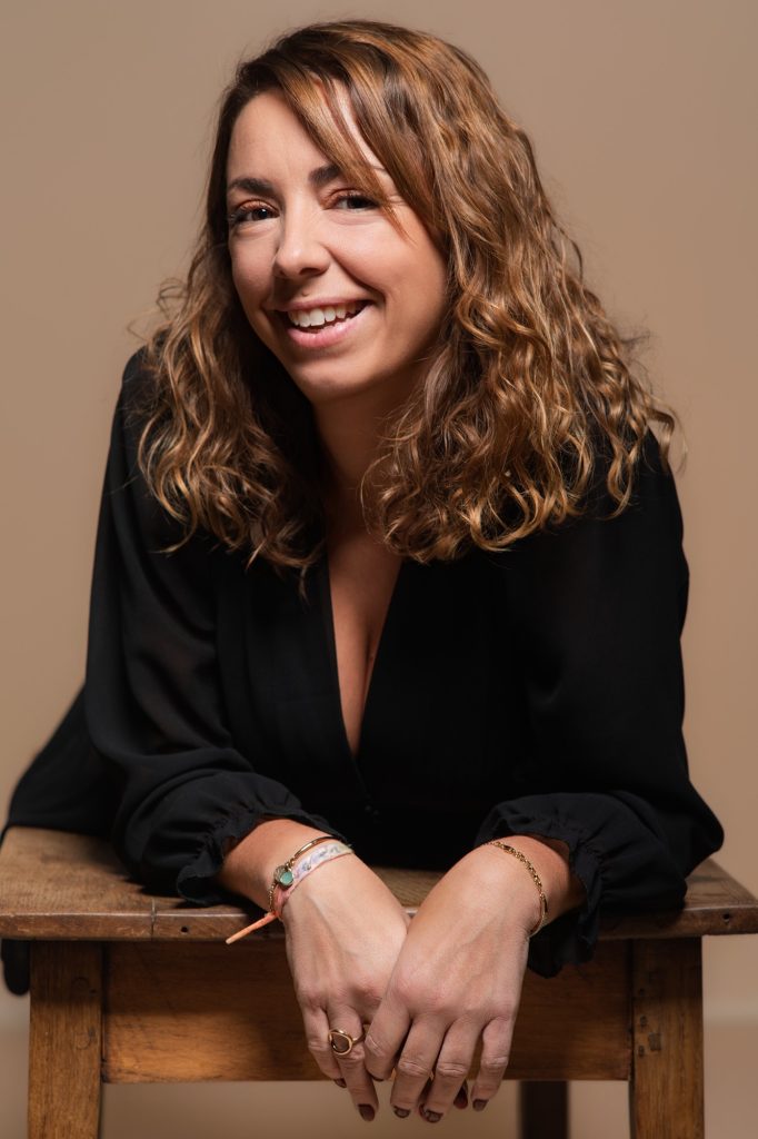 Séance portrait estime de soi avec Vanessa souriante en robe noire de face allongée sur une table