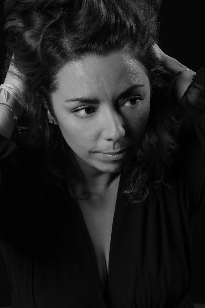 Séance portrait estime de soi avec Vanessa noir et blanc décolletée en robe noire se coiffant de profil