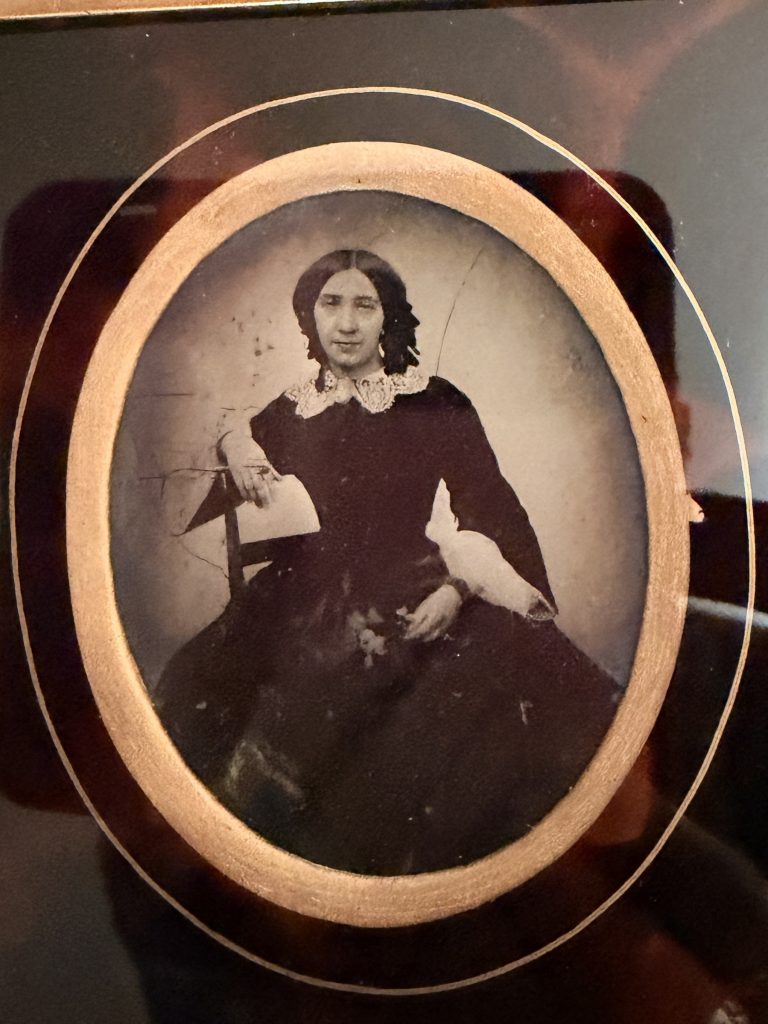 Ambrotype dans un cadre en bois doré, passe-partout ovale à bordure façon écaille : portrait d'une femme assise, cheveux en anglaises et col de dentelle, vers 1855-1865.