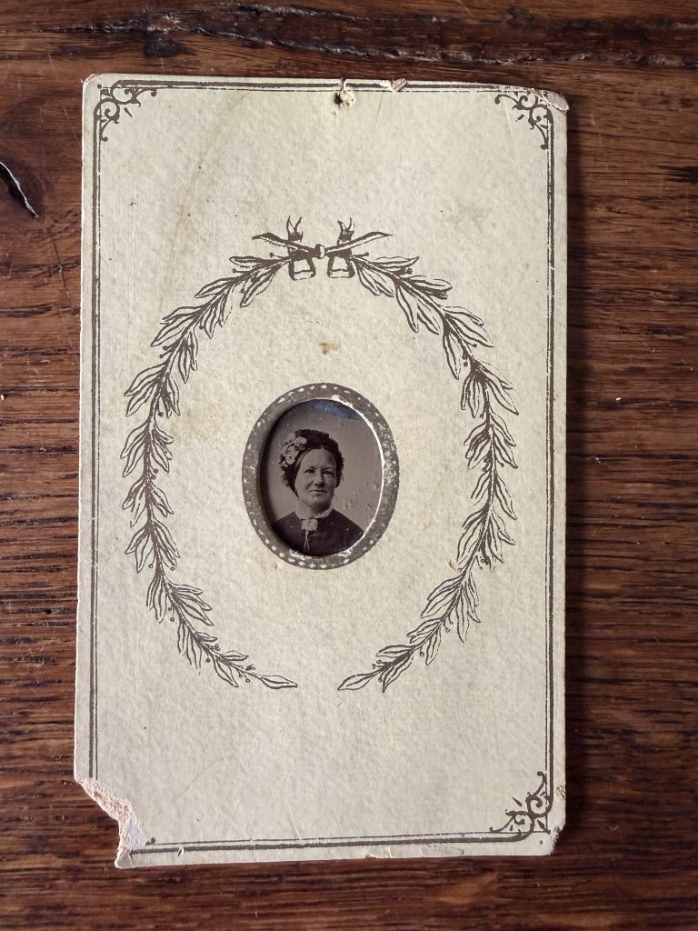 Ferrotype miniature « gem » (~2 cm) serti dans un carton décoratif à couronne de laurier, format carte de visite : portrait d'une femme âgée en bonnet fleuri, vers 1870-1885.