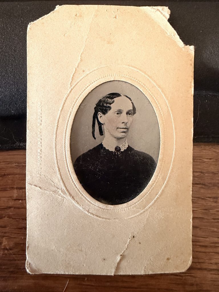 Ferrotype (tintype) sur plaque de fer verni, monté dans un passe-partout carton gaufré à fenêtre ovale : portrait d'une femme d'âge mûr au col de dentelle, États-Unis, vers 1865-1875.